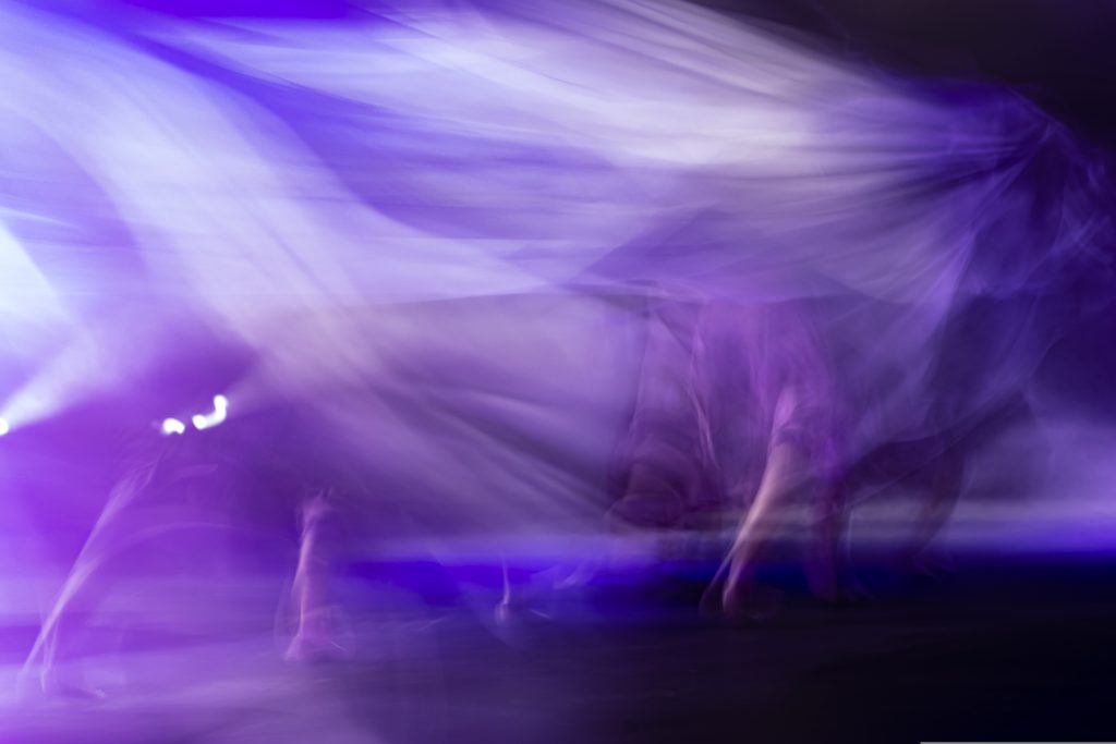 Purple, black, and blue colors are created in this movement blur photo of dancers. 